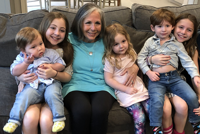Lynne sitting on a couch, holding her grandchildren