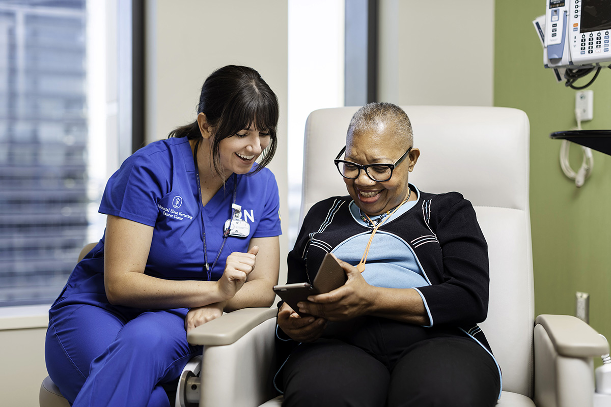 注册护士在检查室与患者一起看着手机屏幕，一起欢笑。 